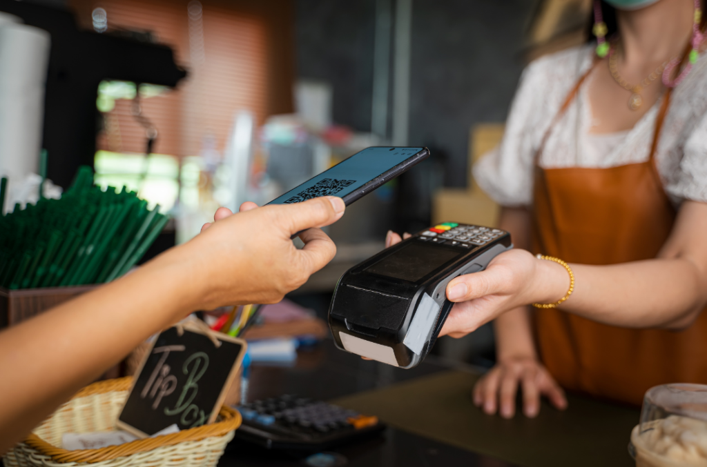 Closeup of a person using their phone to pay at a card machine