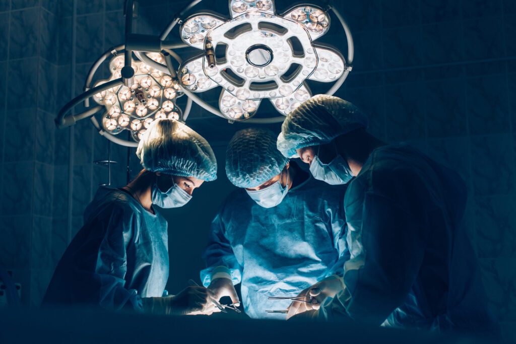 Three surgeons performing an operation wearing full PPE