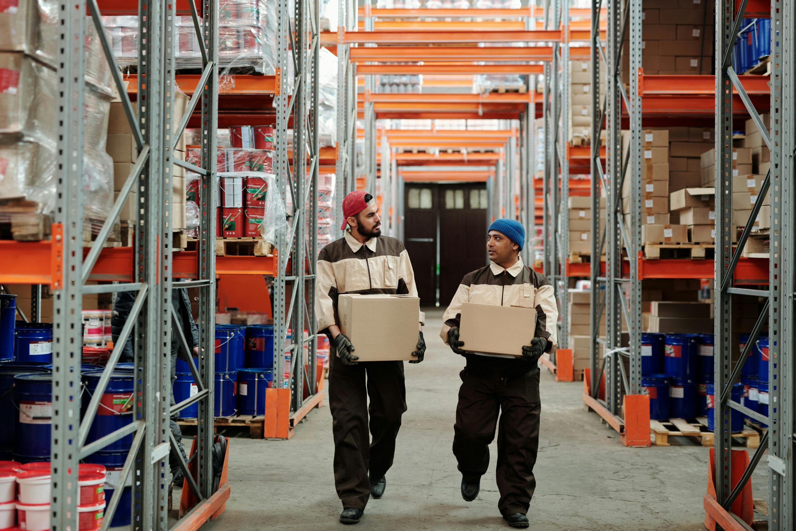 Full warehouse with two men carrying boxes down the central aisle