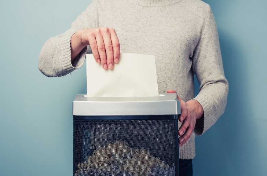 Midshot of a person putting a sheet of paper into a paper shredder