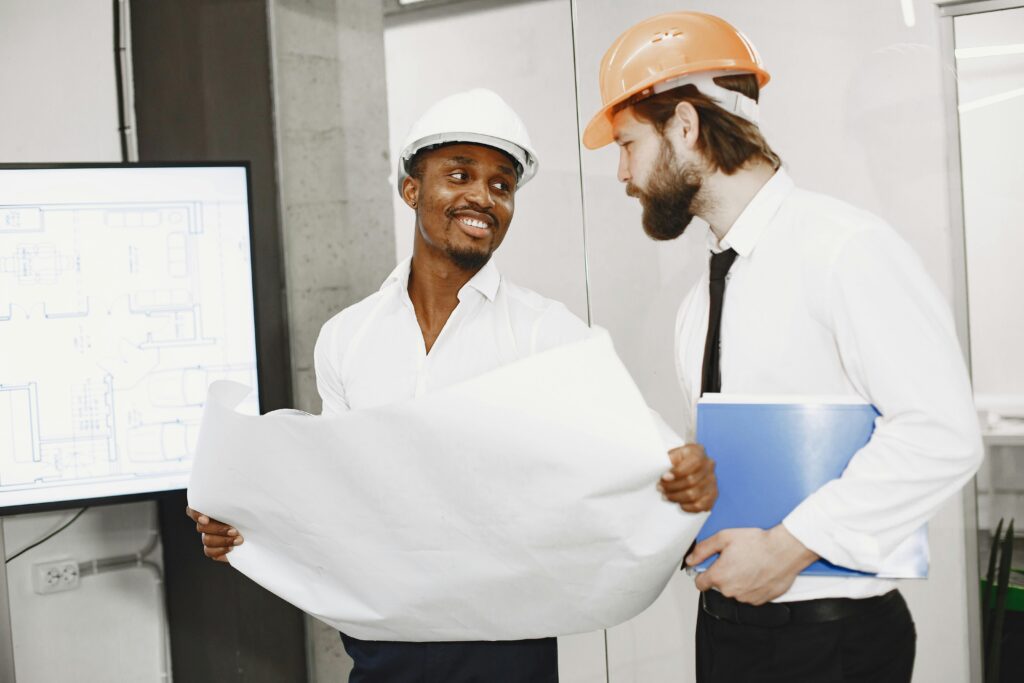 Two men wearing hard hats looking at a schematic for a building construction