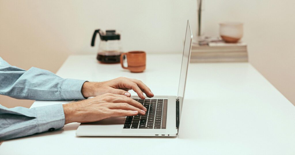 close up of someone typing on a laptop on a clean desk
