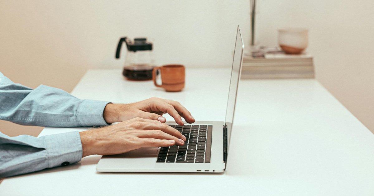 close up of someone typing on a laptop on a clean desk