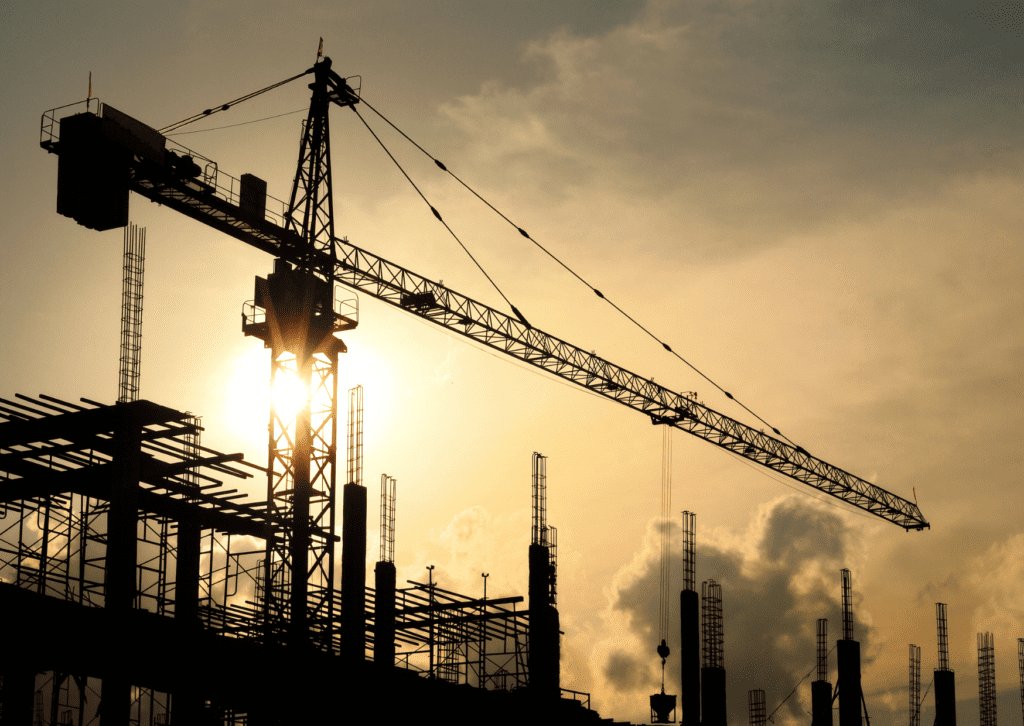 Image of a crane at a building site against the setting sun