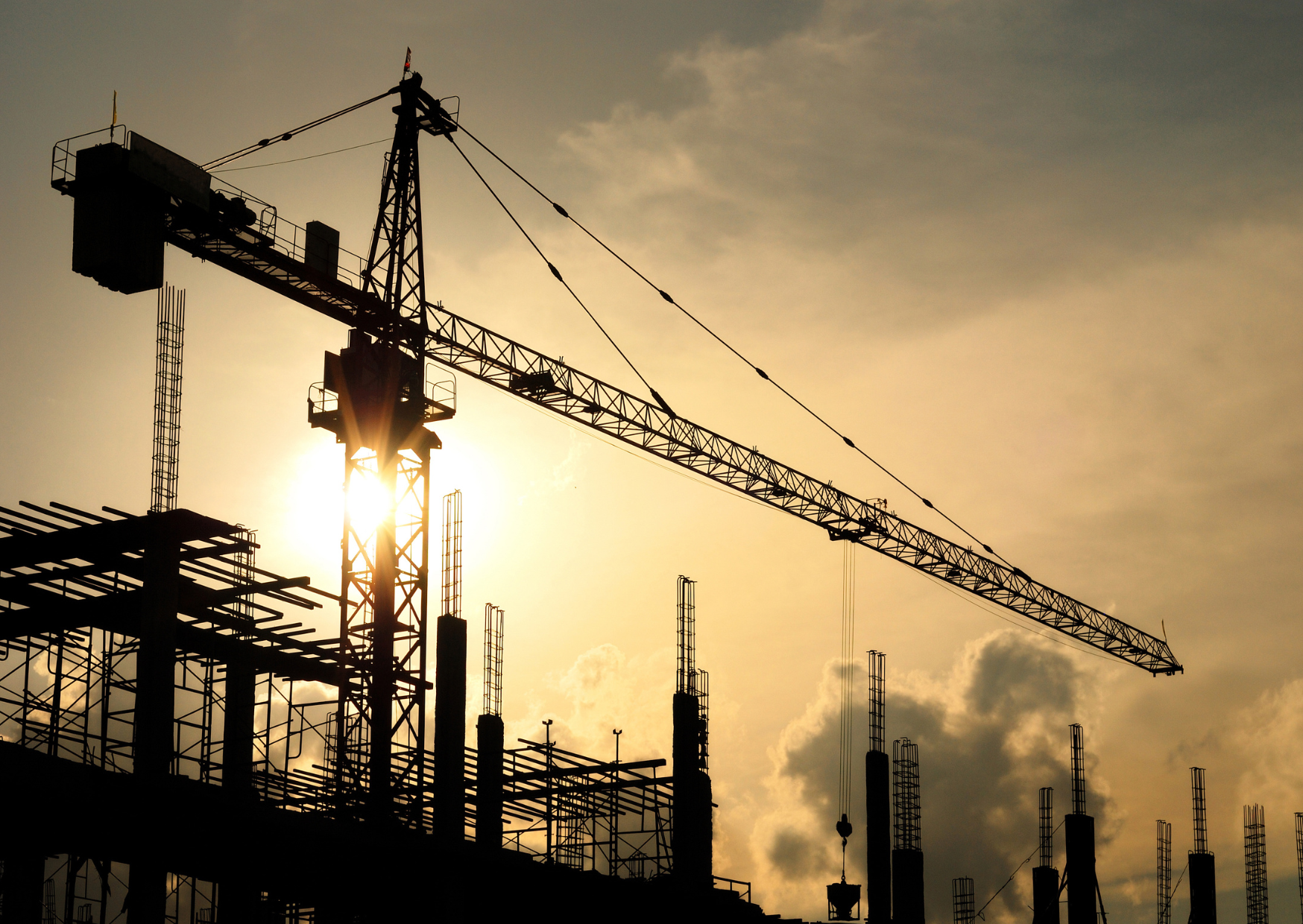 Image of a crane at a building site against the setting sun