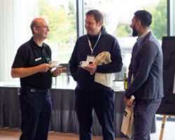 Iain Barker speaking to two attendees of the Solutions Showcase 2024