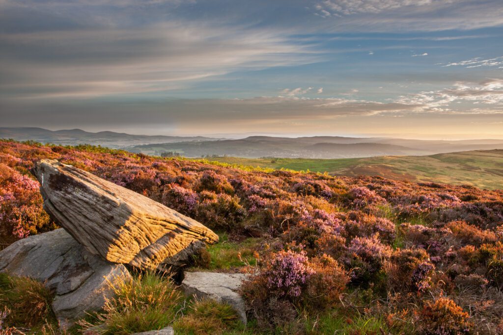 View of the landscape with a large rock in the foreground from the Simonside hills, near Rothbury, Northumberland, UK