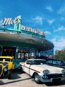 A classic car parked in front of a diner.
