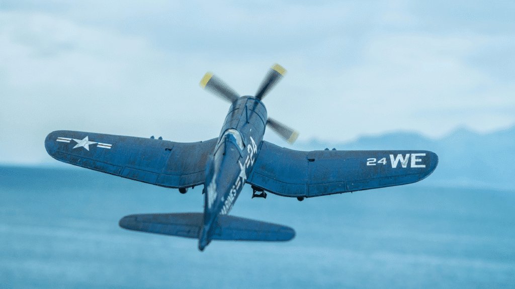 A World War Two fighter plane flies against a backdrop of the sea below and the blue sky above.