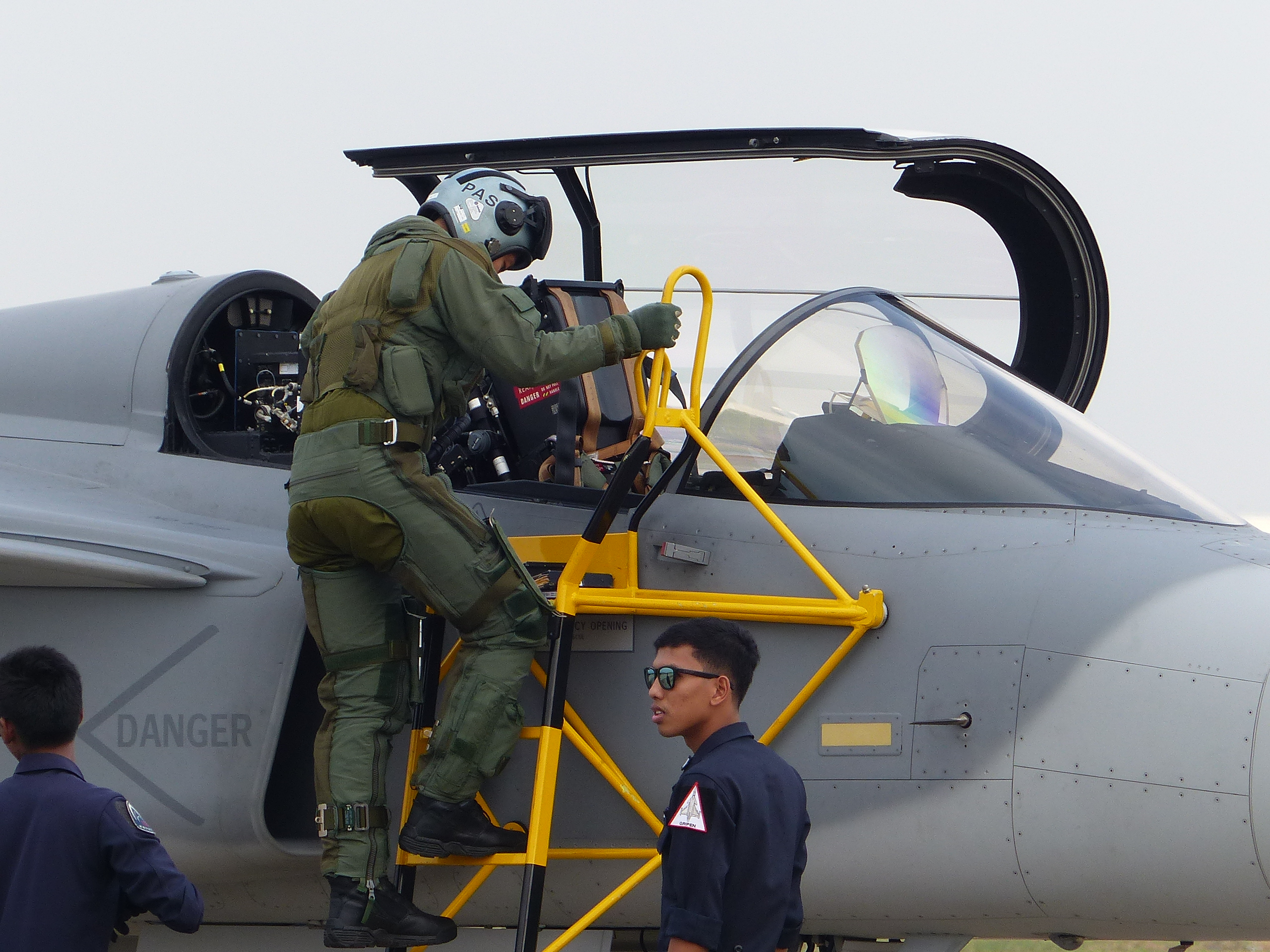 An Airforce pilot climbs a ladder to enter a jet fighter’s cockpit.