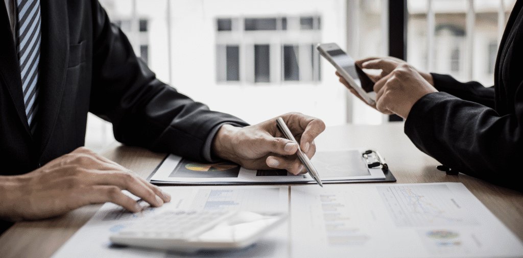 A close-up of two office workers working out expenses at a desk.