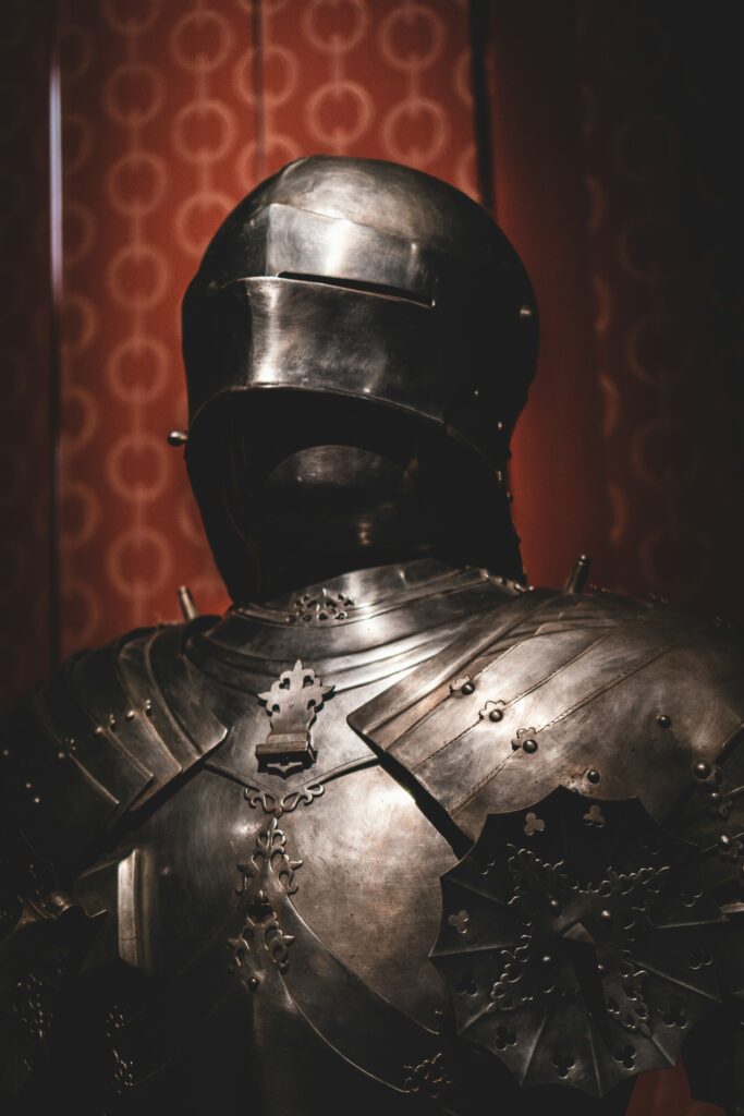Photo of the top of a suit of armour showing the helmet with slits for eye holes and many layers of plates of metal