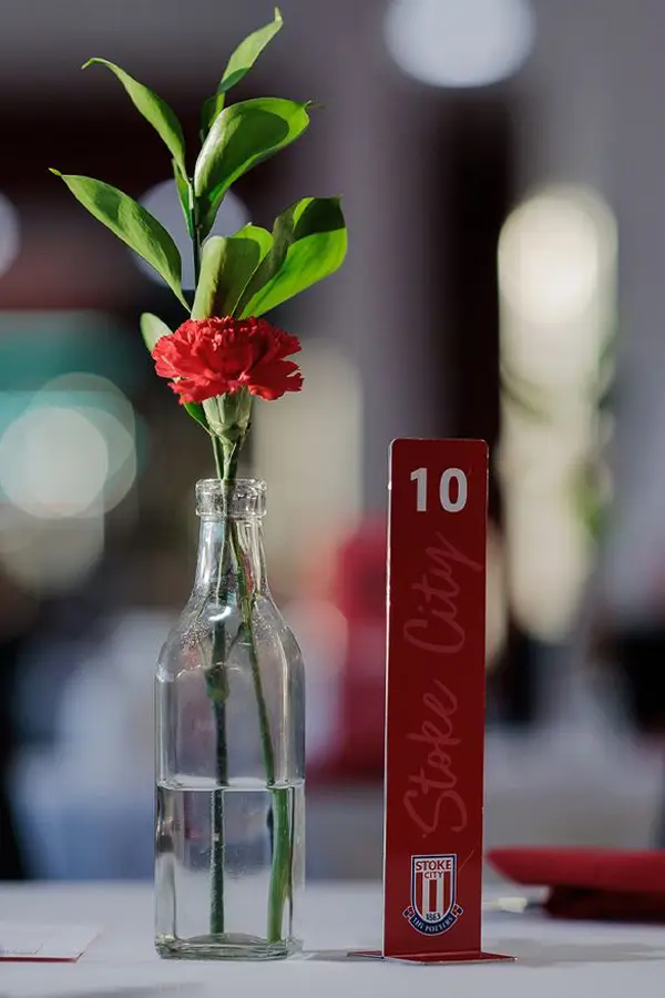 Stoke City Football Club venue interior showing a flower in a glass bottle on a table with a table sign