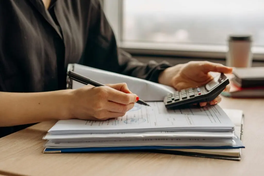 Stock photo of a woman working on paperwork and using a handheld calculator