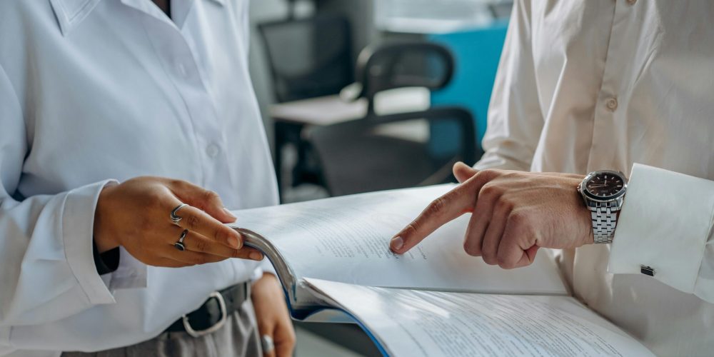 Stock photo of two people looking at something in a folder of printed documents